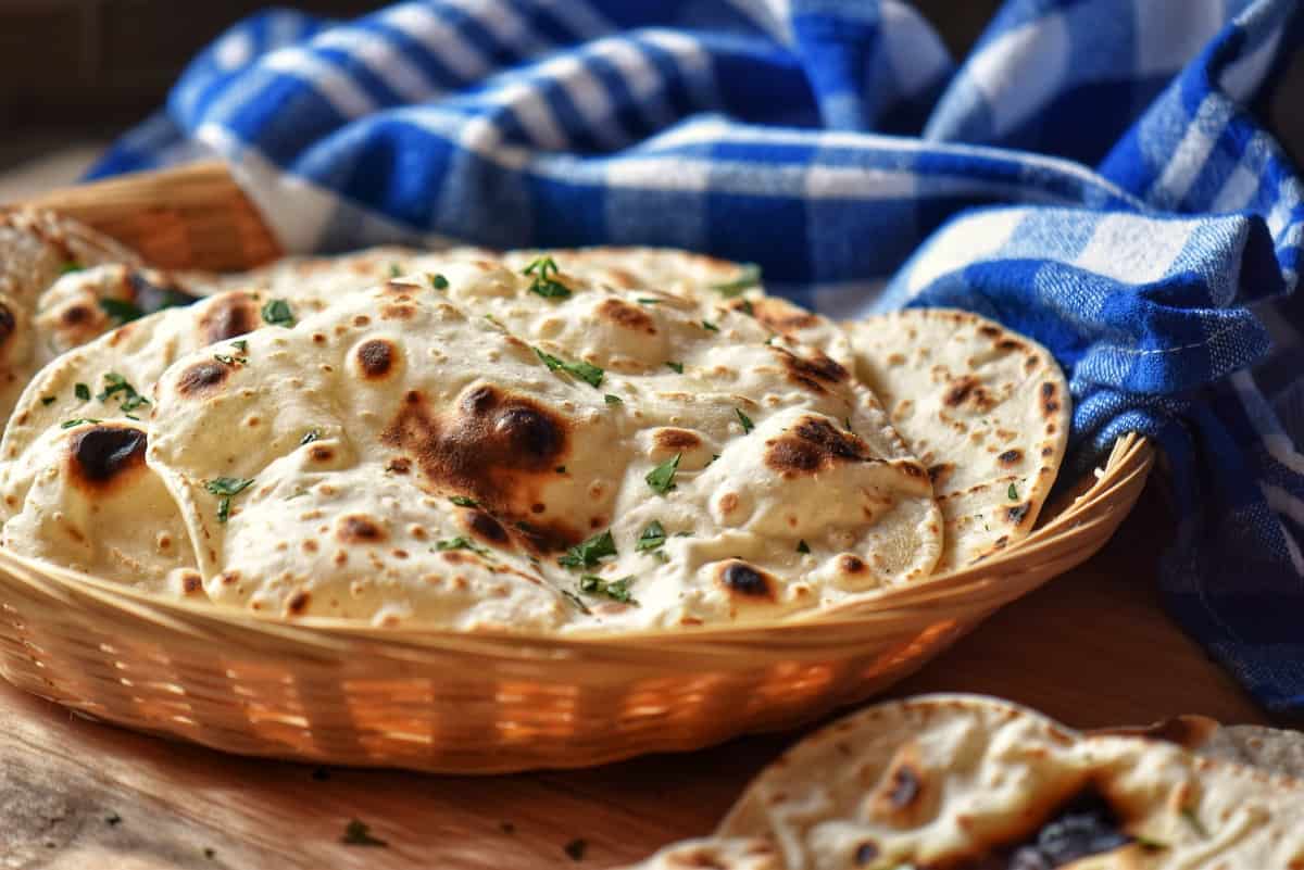 A pile of flatbreads in a wicker basket.