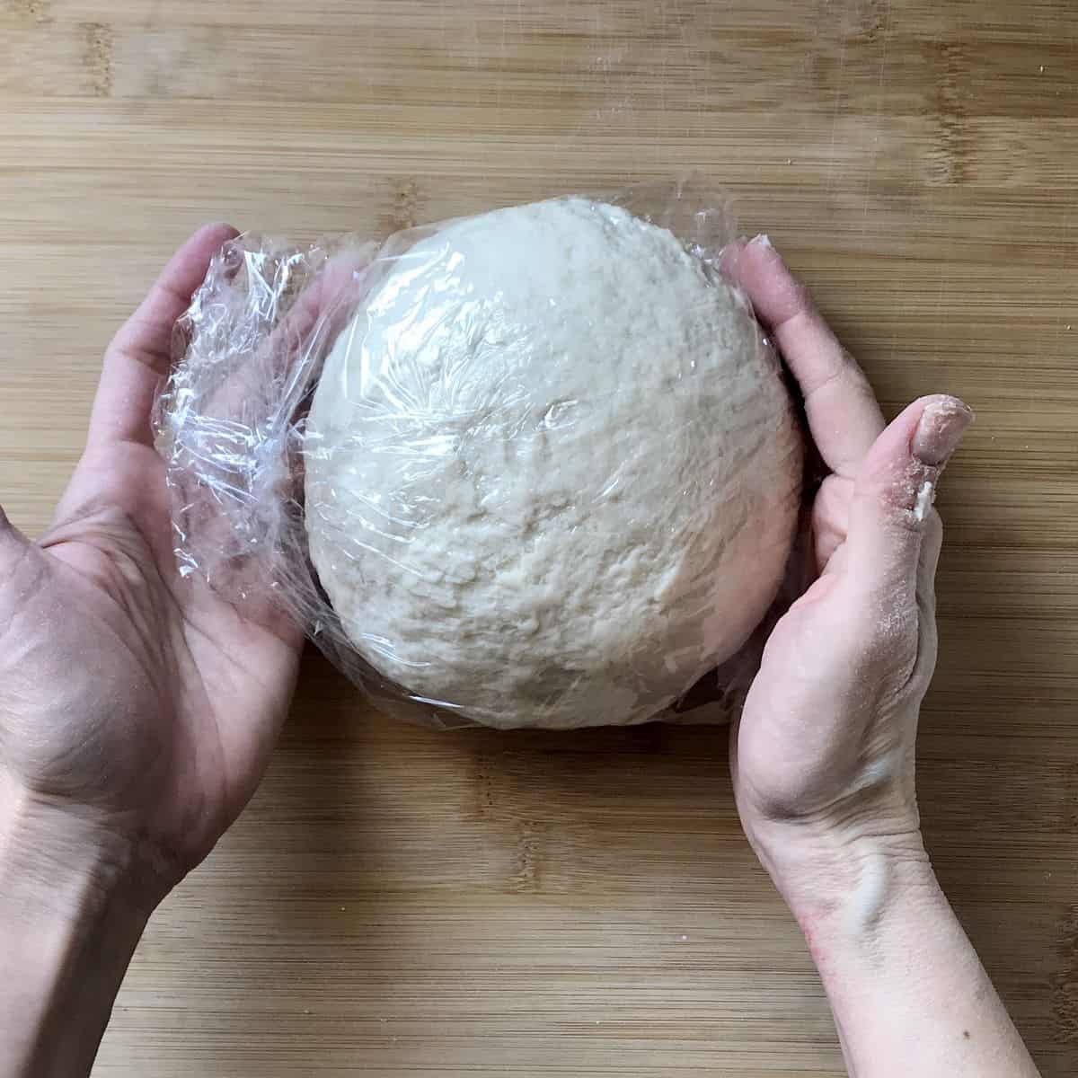 A piece of plastic film is placed around a ball of cavatelli dough.