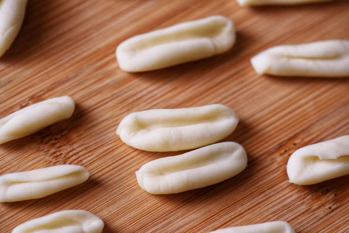 Freshly formed cavatelli on a wooden board.