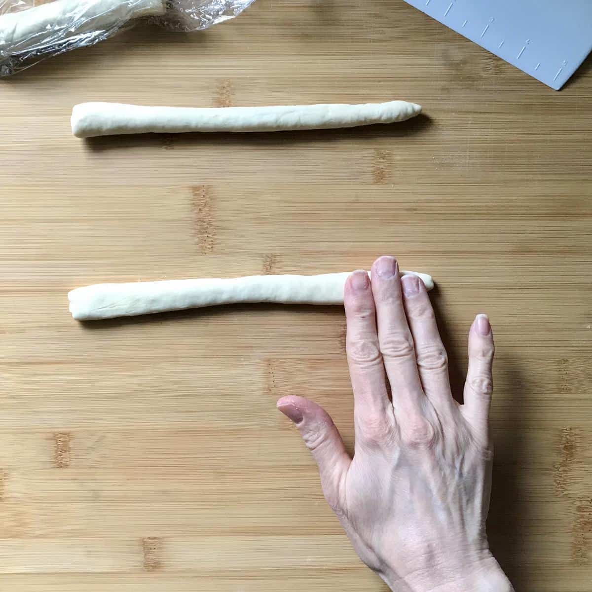 The top of a rope of cavatelli dough being slightly flattened.