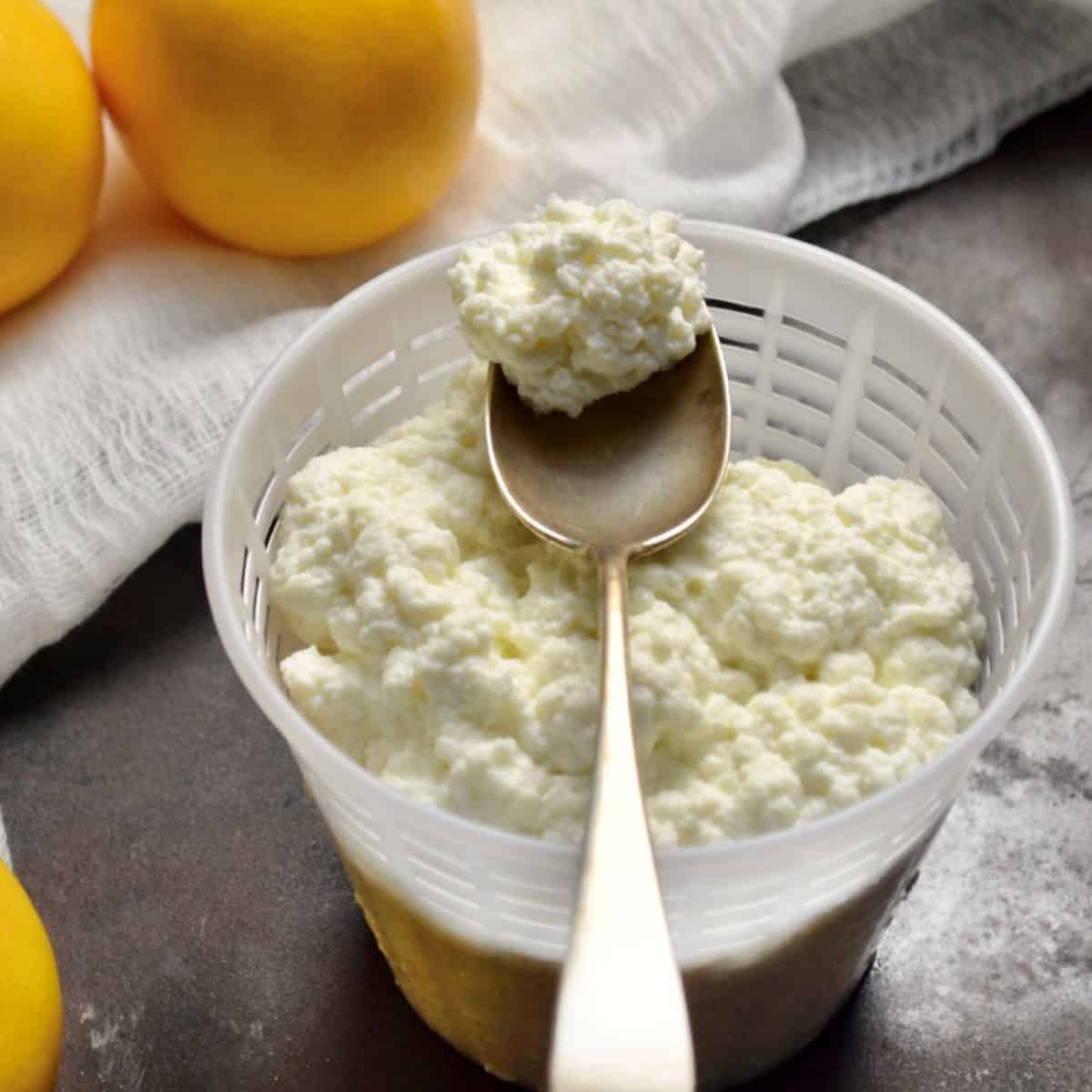 A spoonful of freshly made homemade ricotta cheese over a cheese basket.