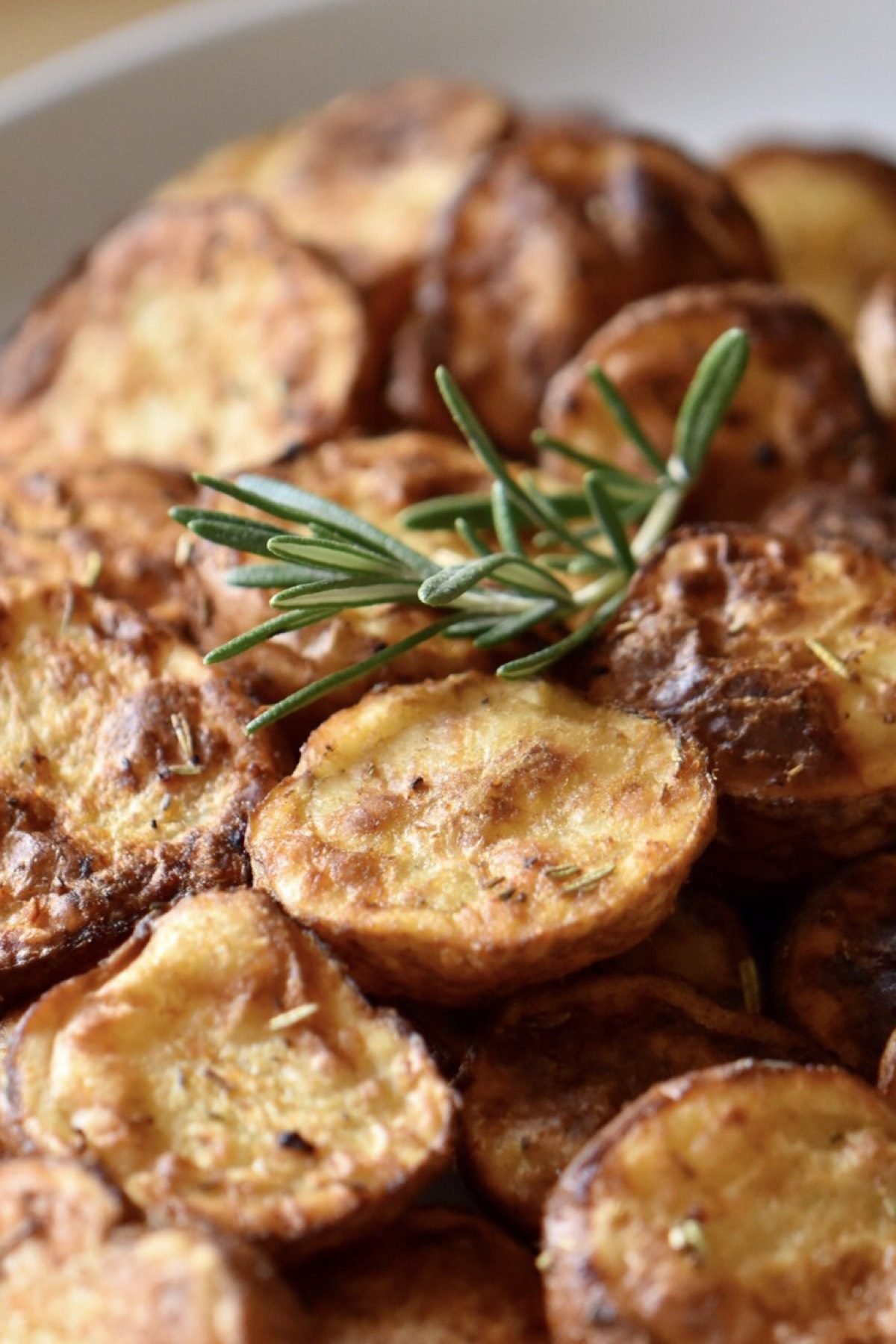 A pile of Air Fryer Potatoes garnished with a twig of rosemary.