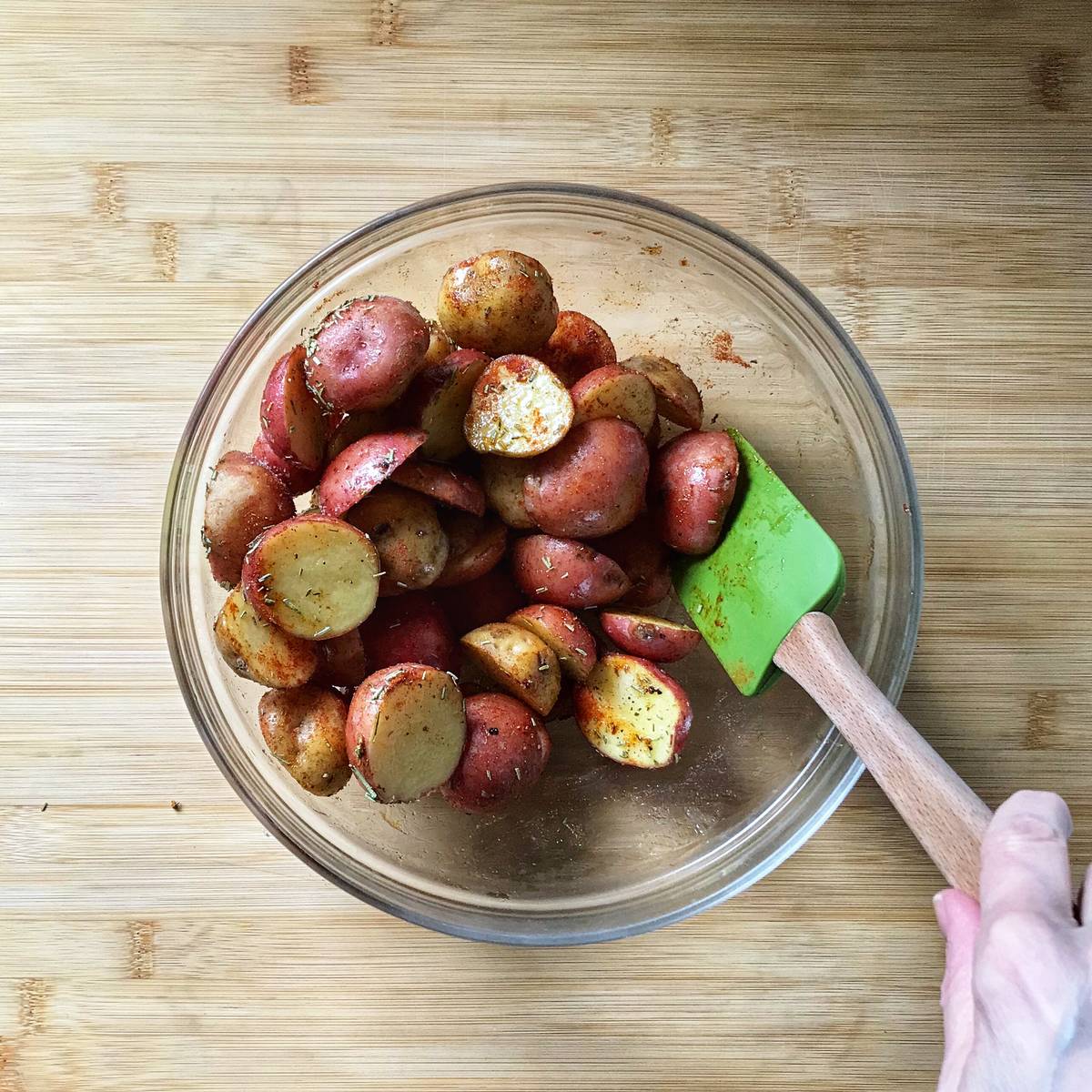 Creamer potatoes tossed with dried herbs in a large bowl.