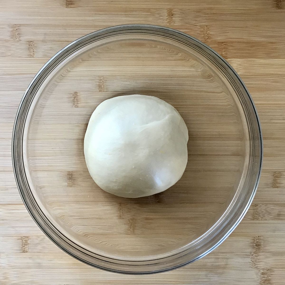 Ball of dough resting in a large bowl.