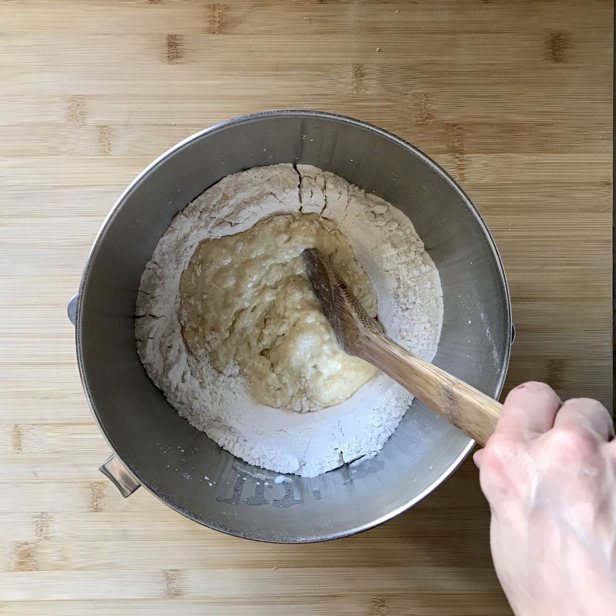 The liquid ingredients mixed with the dry ingredients in a bowl of a stand mixer. 