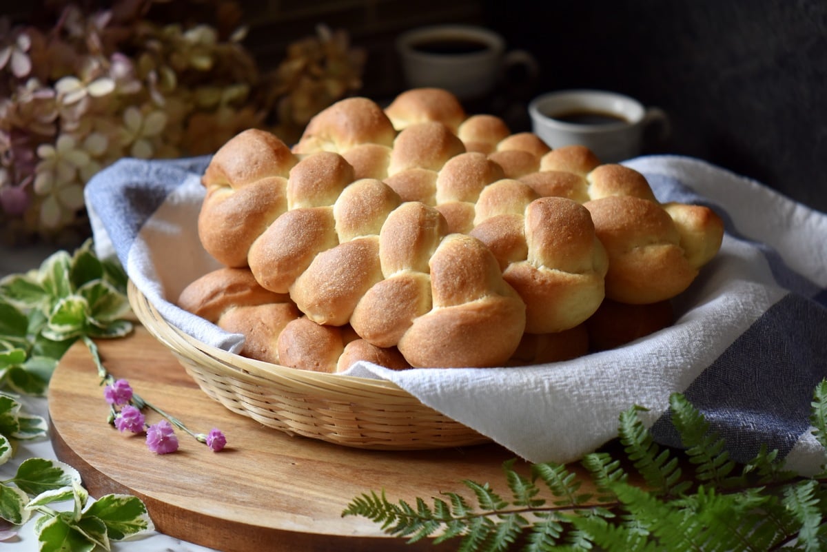 Braided mini loaves of sweet bread piled high in a wicker basker.