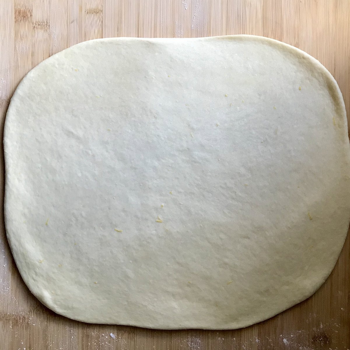 Stretched out dough on a wooden board.