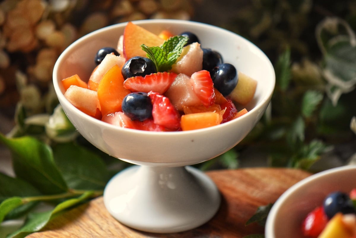 A rainbow of fresh fruit salad in a white dish. 