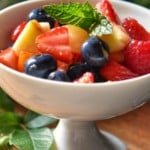 A rainbow of fresh fruit salad in a white dish.