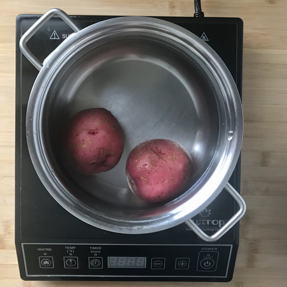 Two red potatoes in a pot of water.
