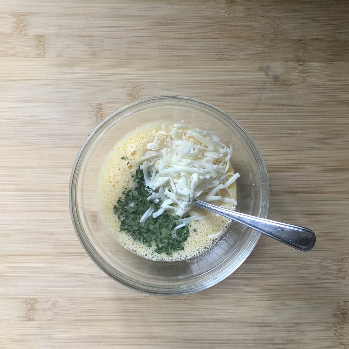 Eggs, cheese and parsley being combined in a bowl.