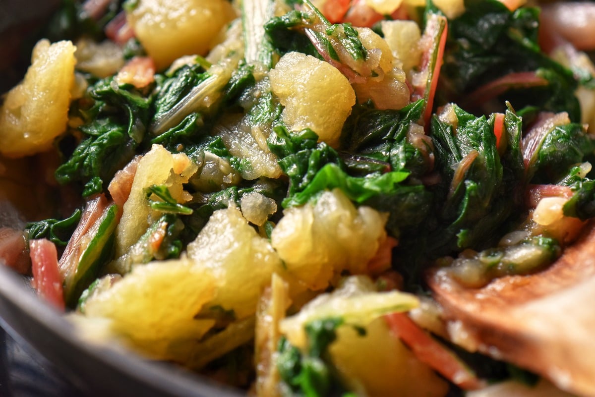 A close up photo of cooked Swiss chard mixed with potatoes.