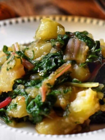 Swiss chard and potatoes in a white dish.