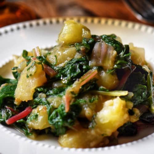 Swiss chard and potatoes in a white dish.