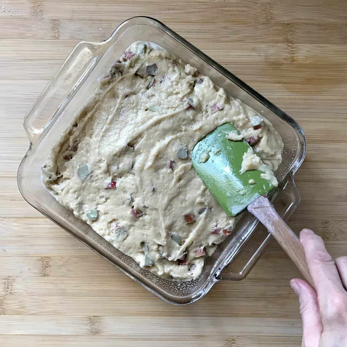 Rhubarb cake batter in a glass baking pan.