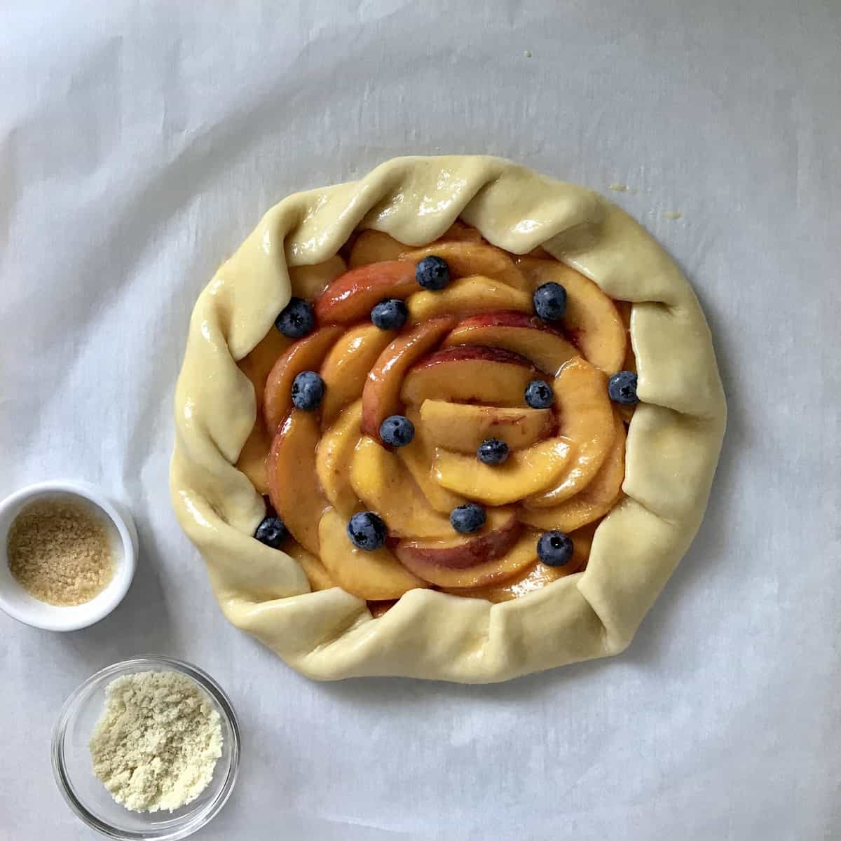 An uncooked Italian peach tart on parchment paper.