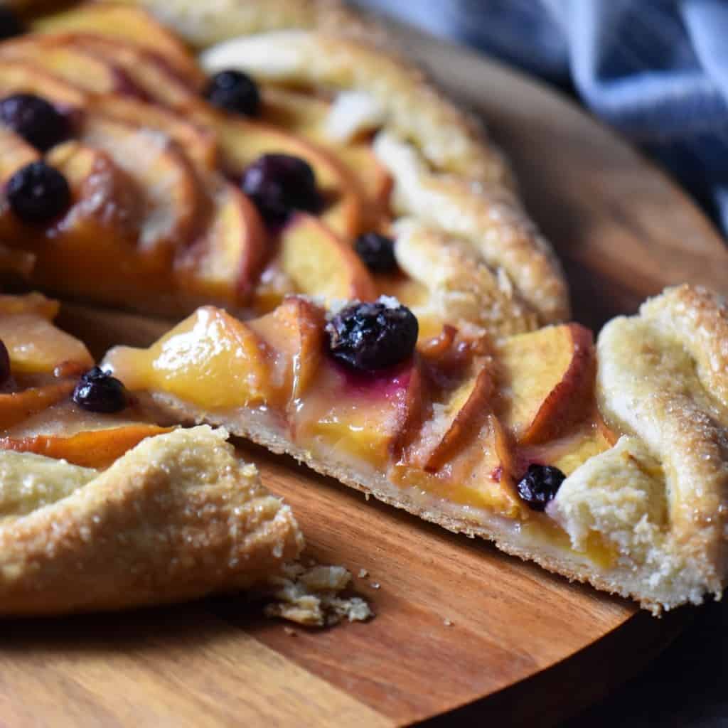 A rustic Italian tart with peaches on a wooden board.