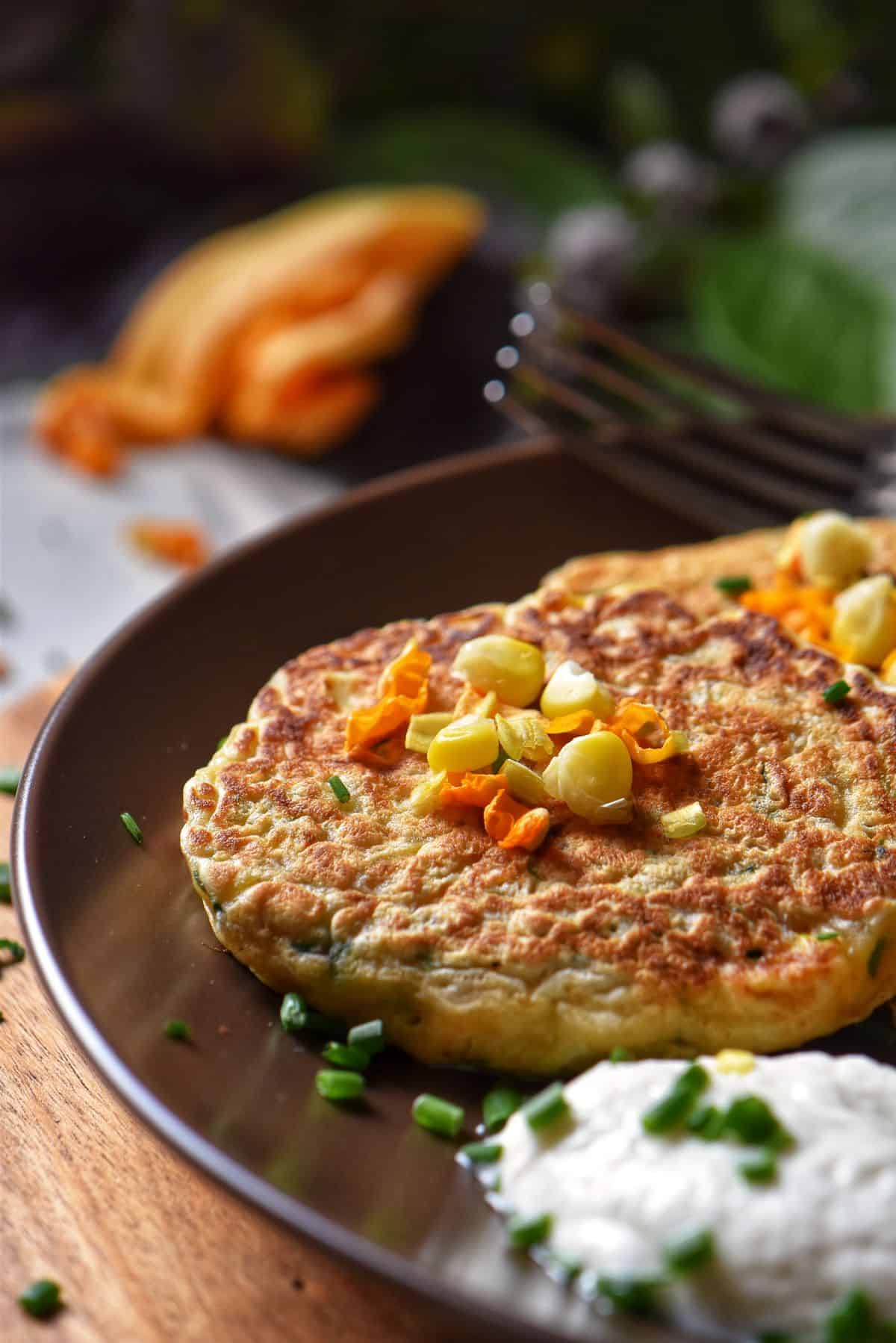 Zucchini pancakes and yogurt sauce in a dinner plate.