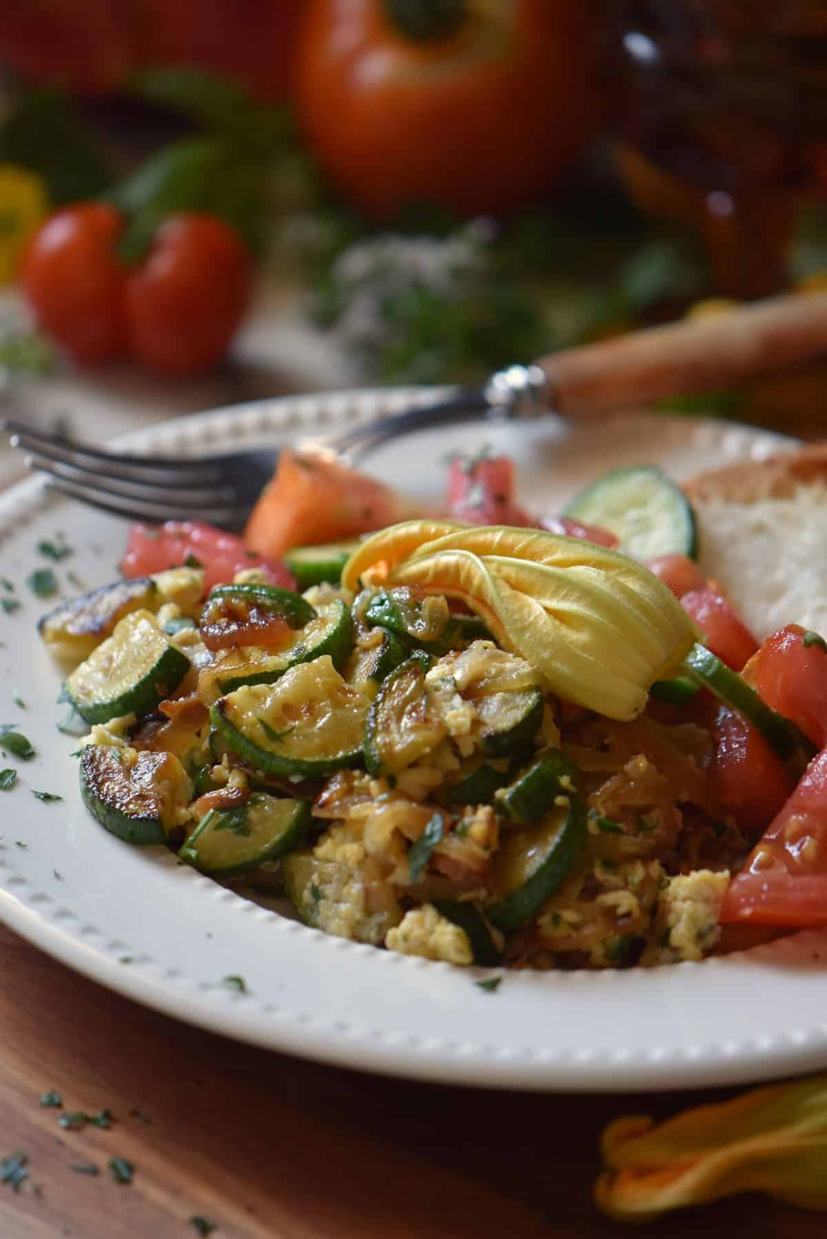 A white plate filled with sauteed zucchini and eggs.