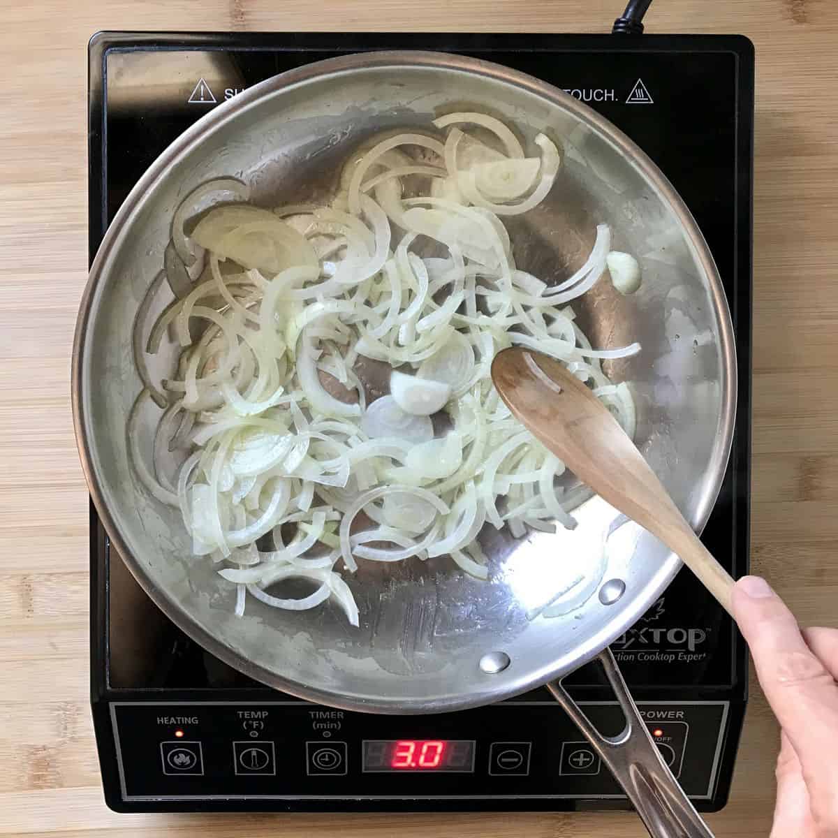 Sliced onions being sauteed in a pan.
