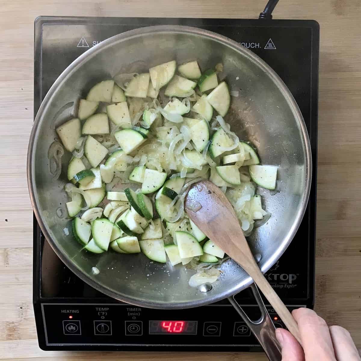Quartered zucchini being sauteed with sliced onions. 