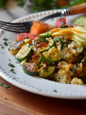 A white plate filled with sauteed zucchini and eggs.