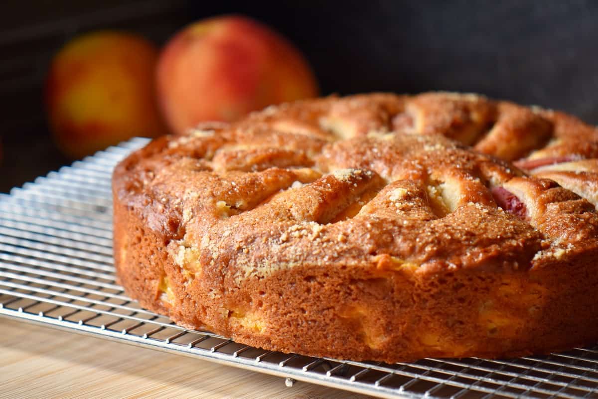 A peach cake on a cooling rack.