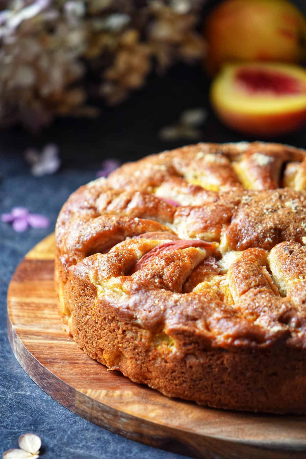 A round peach cake on a wooden board.