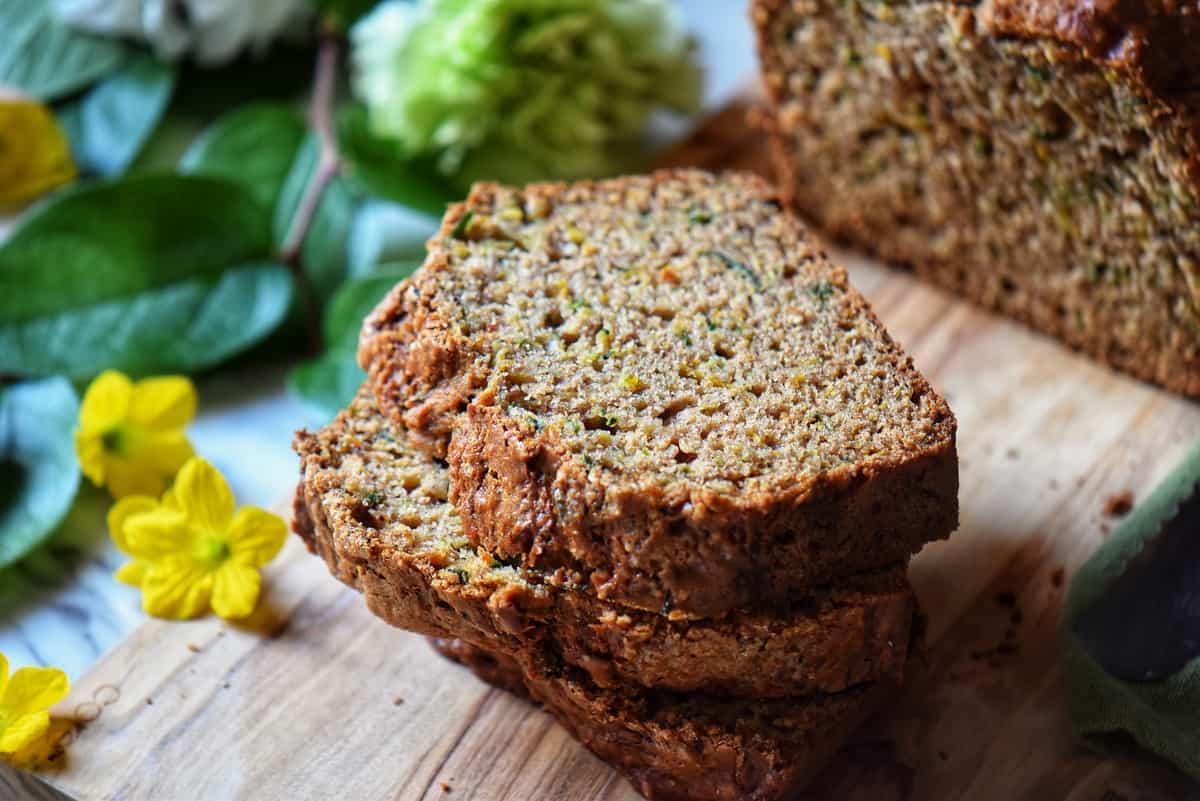 Stacked slices of zucchini loaf on a wooden board.