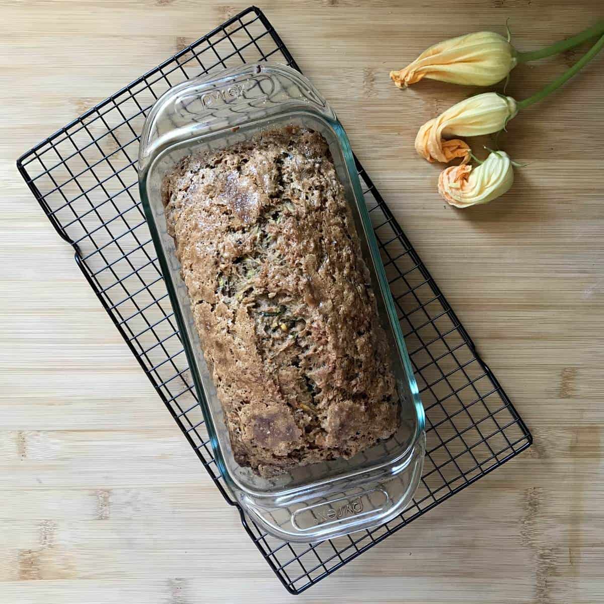 Zucchini bread in a pan on a cooling rack.