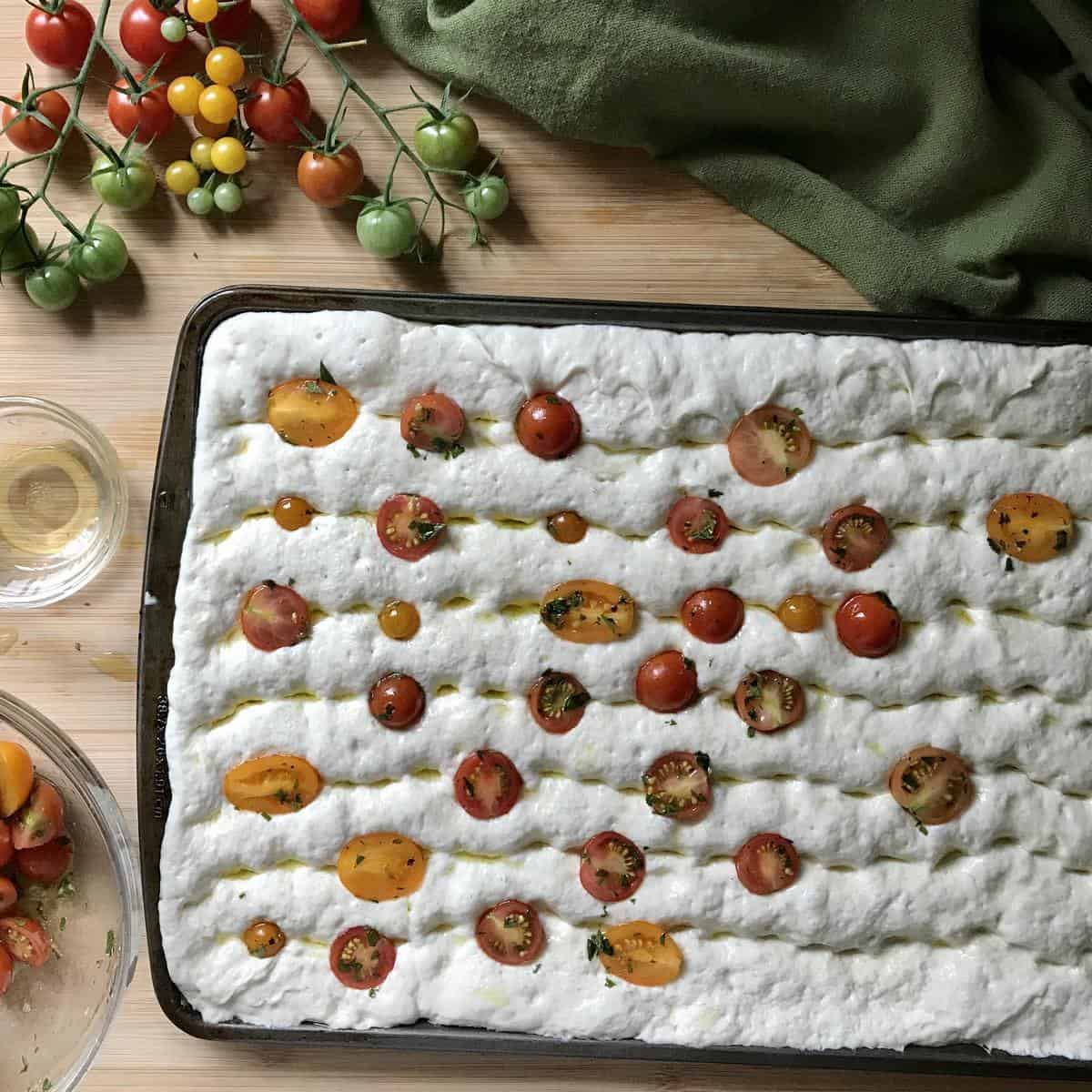 Sliced cherry tomatoes placed in the focaccia dough.