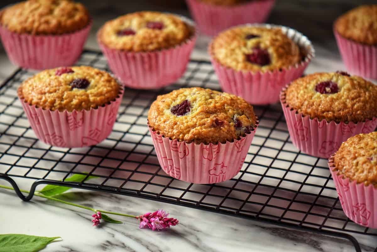 Raspberry muffins cooling off on a wire rack.