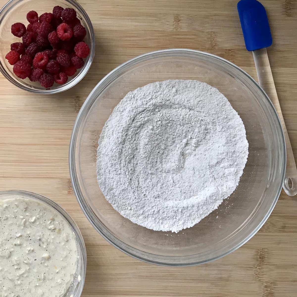 The raspberries along with the wet and dry ingredients in separate bowls.