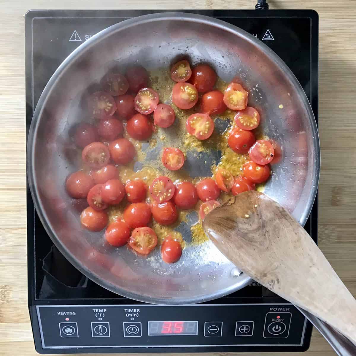 Cherry tomatoes being sauteed in a pan.