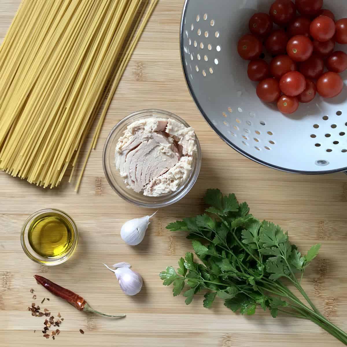 Some of the ingredients to make a tuna pasta recipe on a wooden table. 