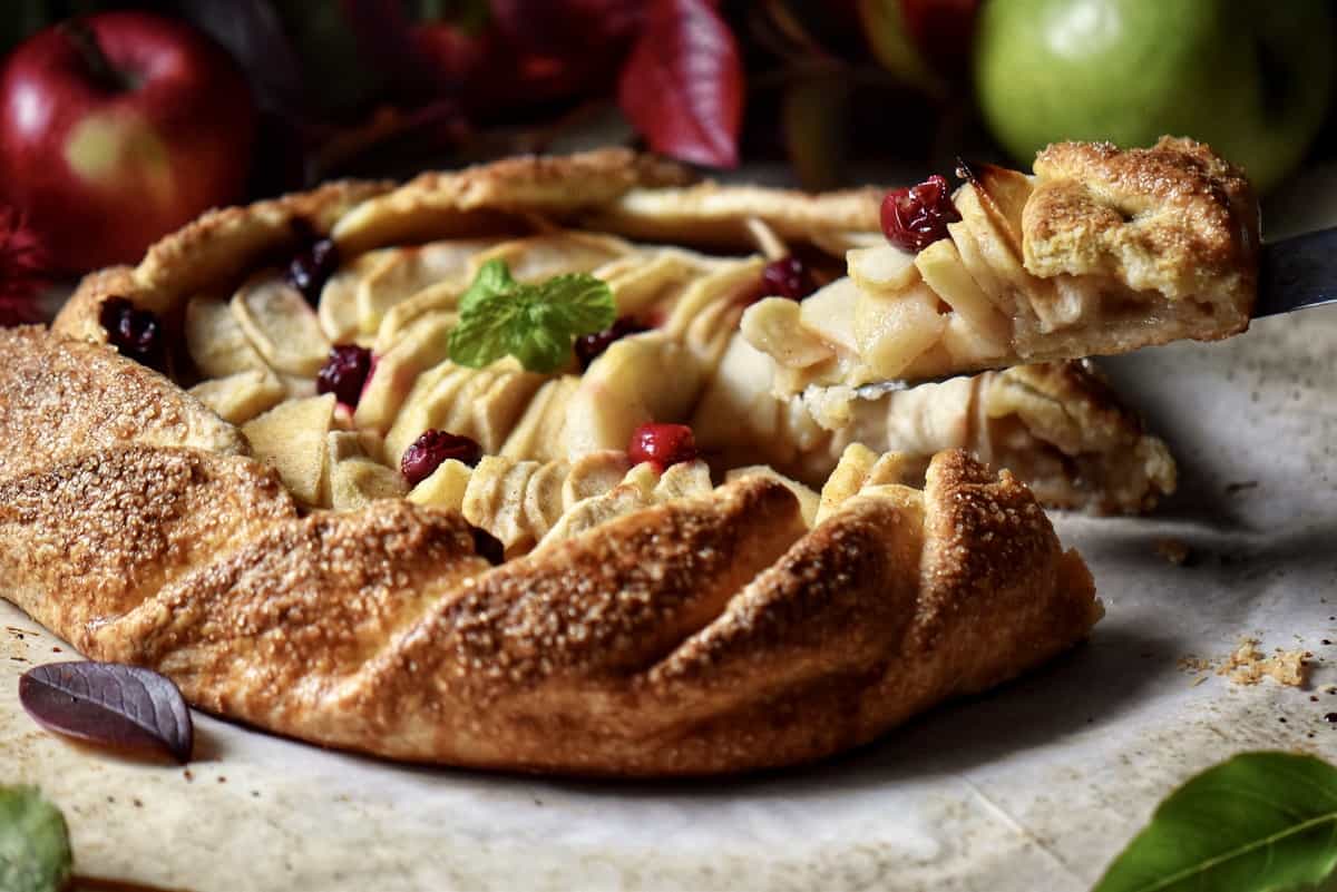 A slice of apple crostata being lifted up.