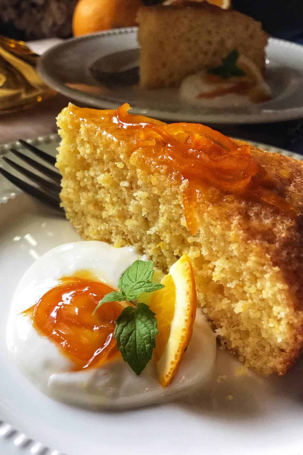A slice of cake next to whipped ricotta, topped with orange syrup.