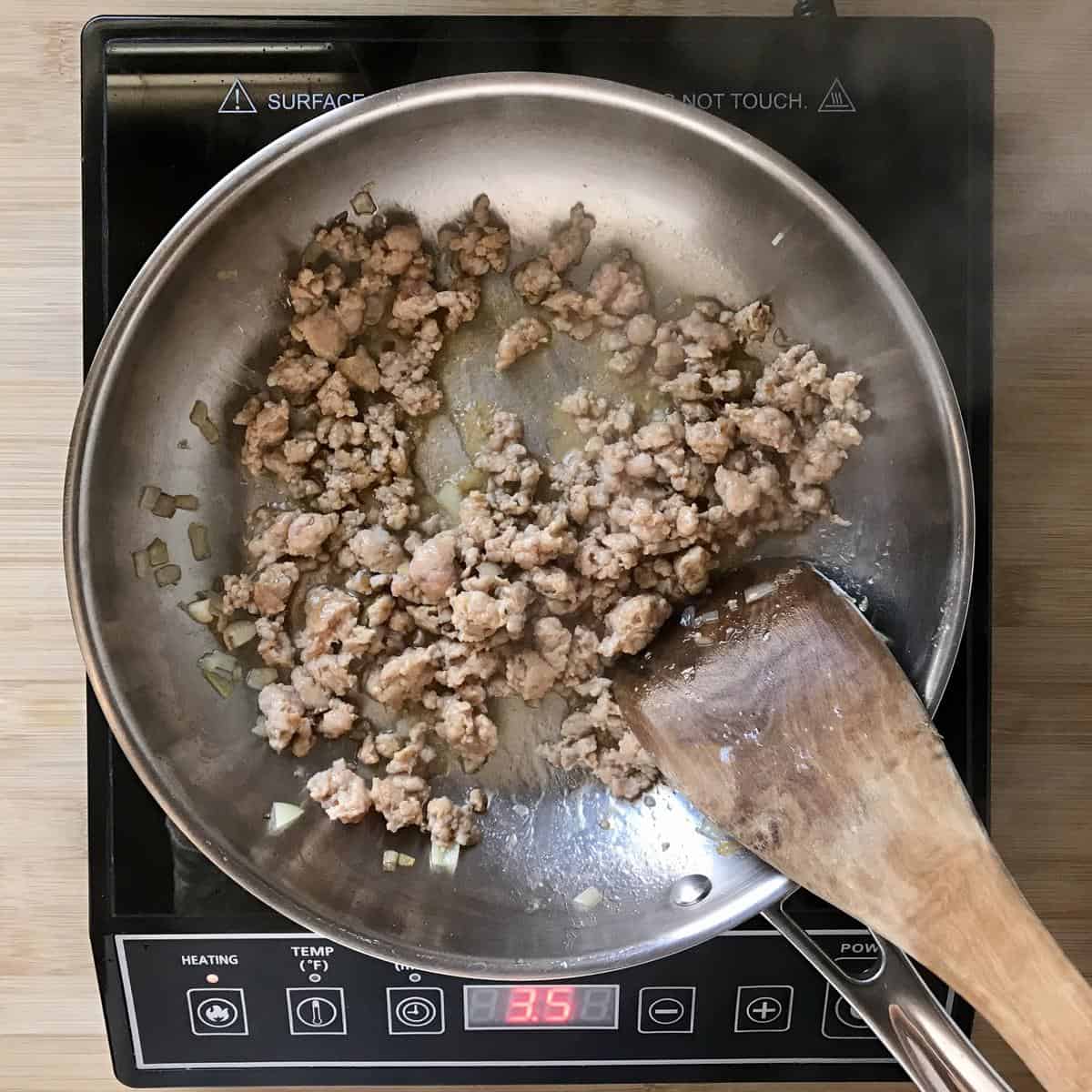 Italian sausage being sauteed in a pan.