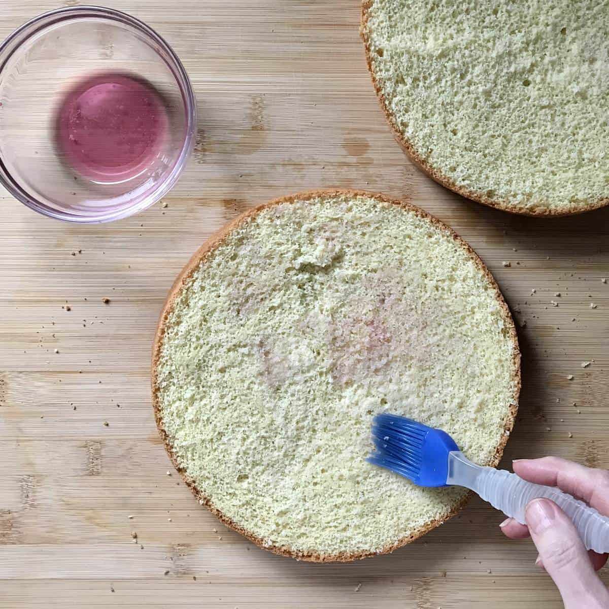 Alcohol being brushed on a sponge cake. 