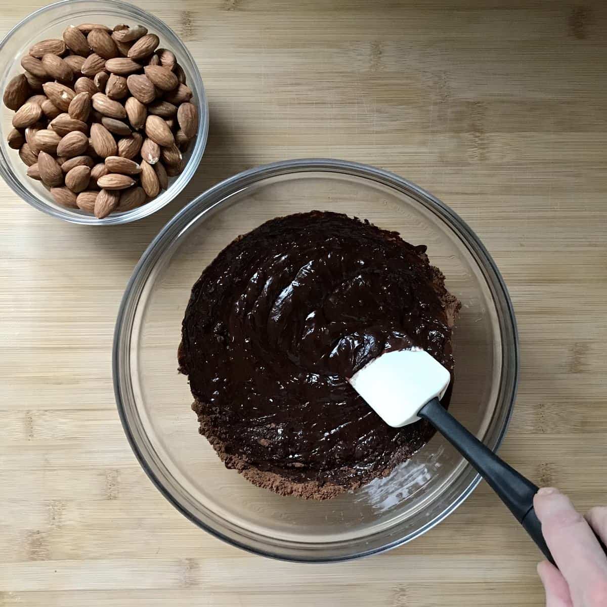 Roasted almonds and melted dark chocolate in bowls. 
