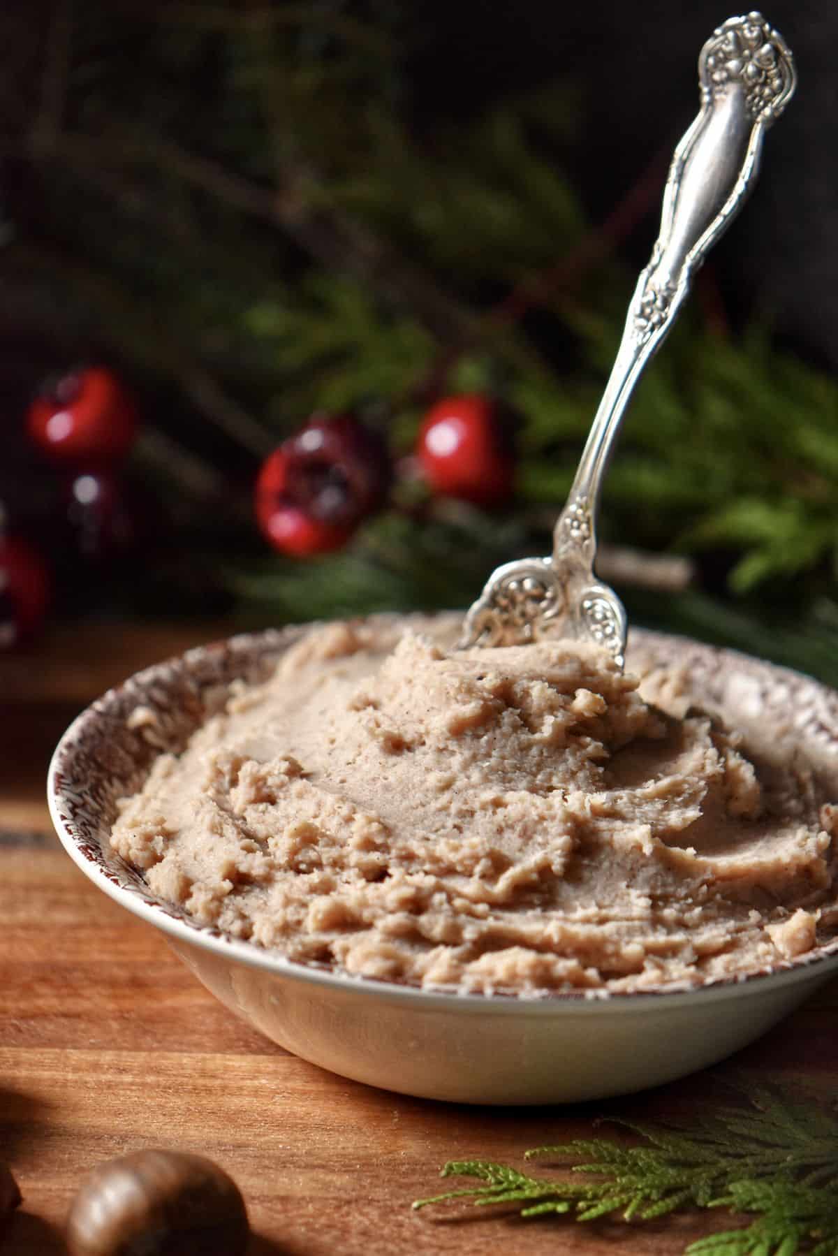 A bowl of pureed chestnuts with a spoon. 