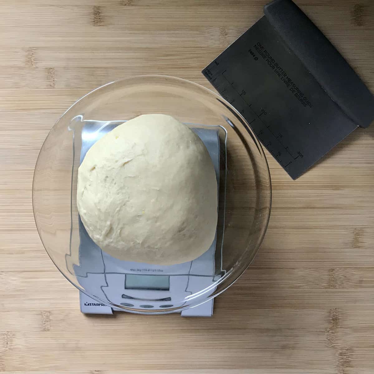 A ball of yeast dough being weighed on a scale. 