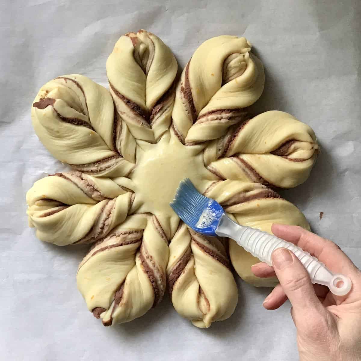 Egg wash being brushed on a star bread.