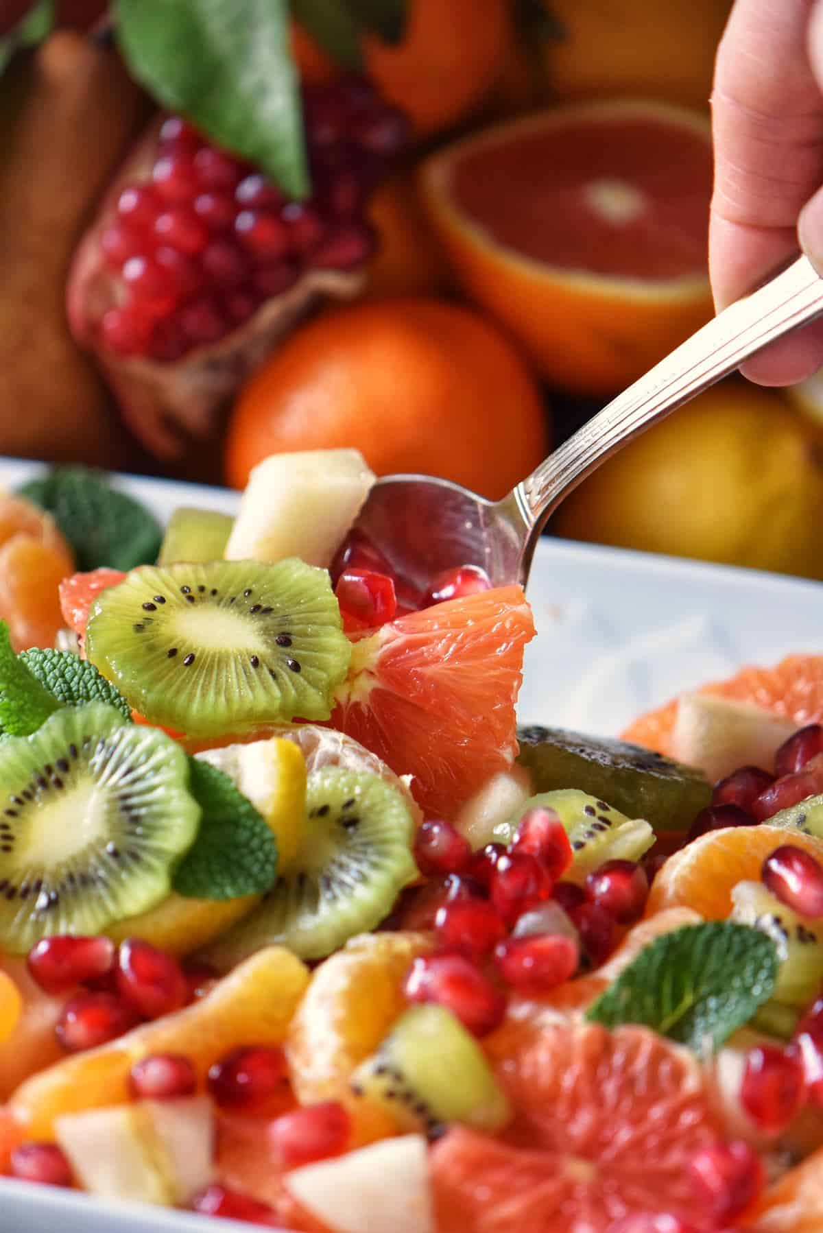 Fruit salad being picked up with a spoon. 