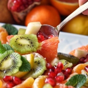 Fruit salad being picked up with a spoon.