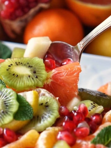 Fruit salad being picked up with a spoon.