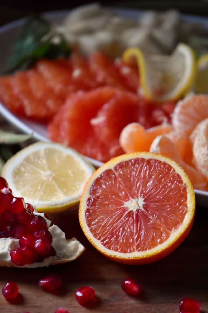 Cara Cara oranges, lemons and a pomegranate being prepared to make a winter fruit salad.