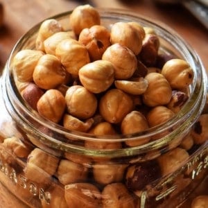 A close up of roasted hazelnuts in a mason jar.