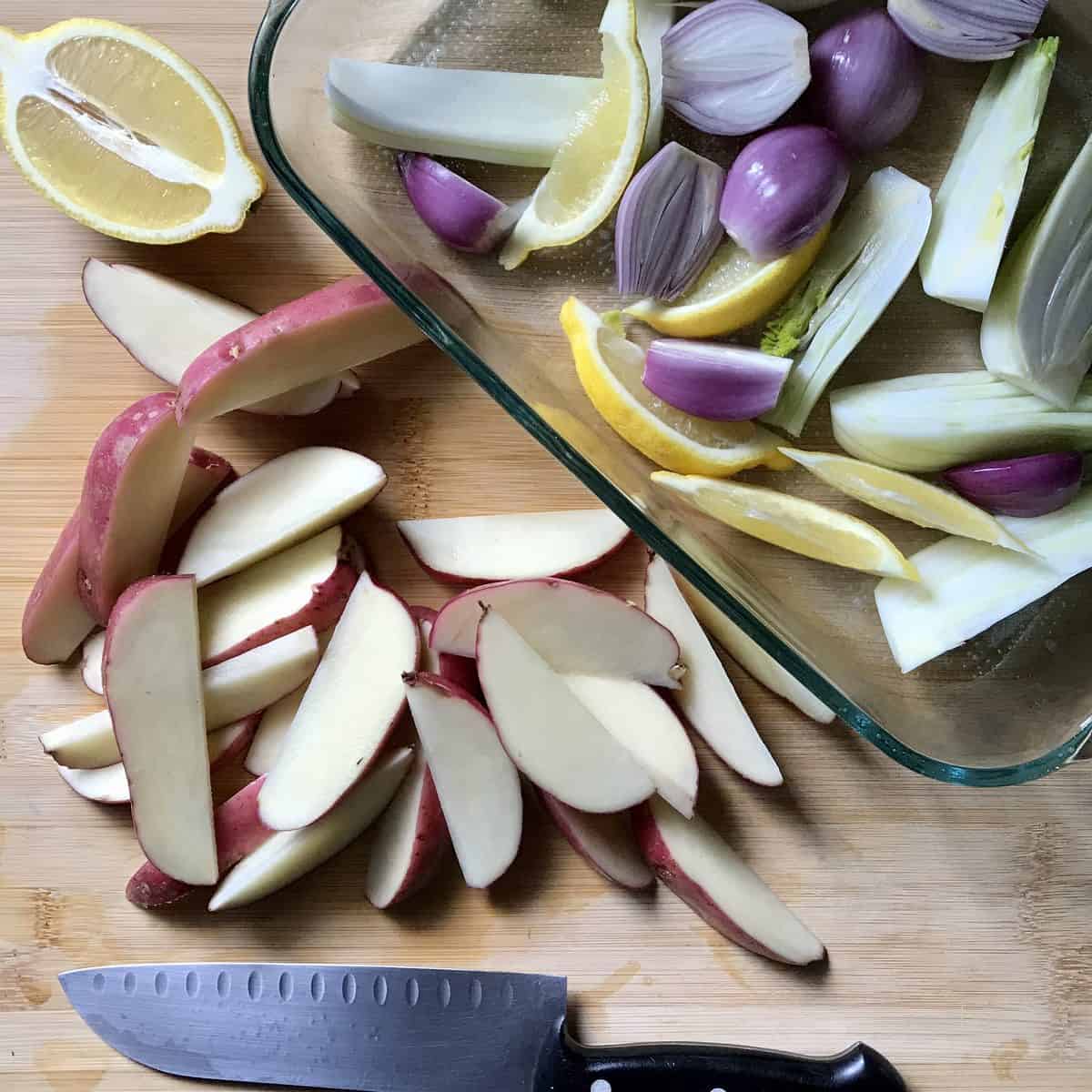 Sliced vegetables on a cutting board and in a baking dish. 
