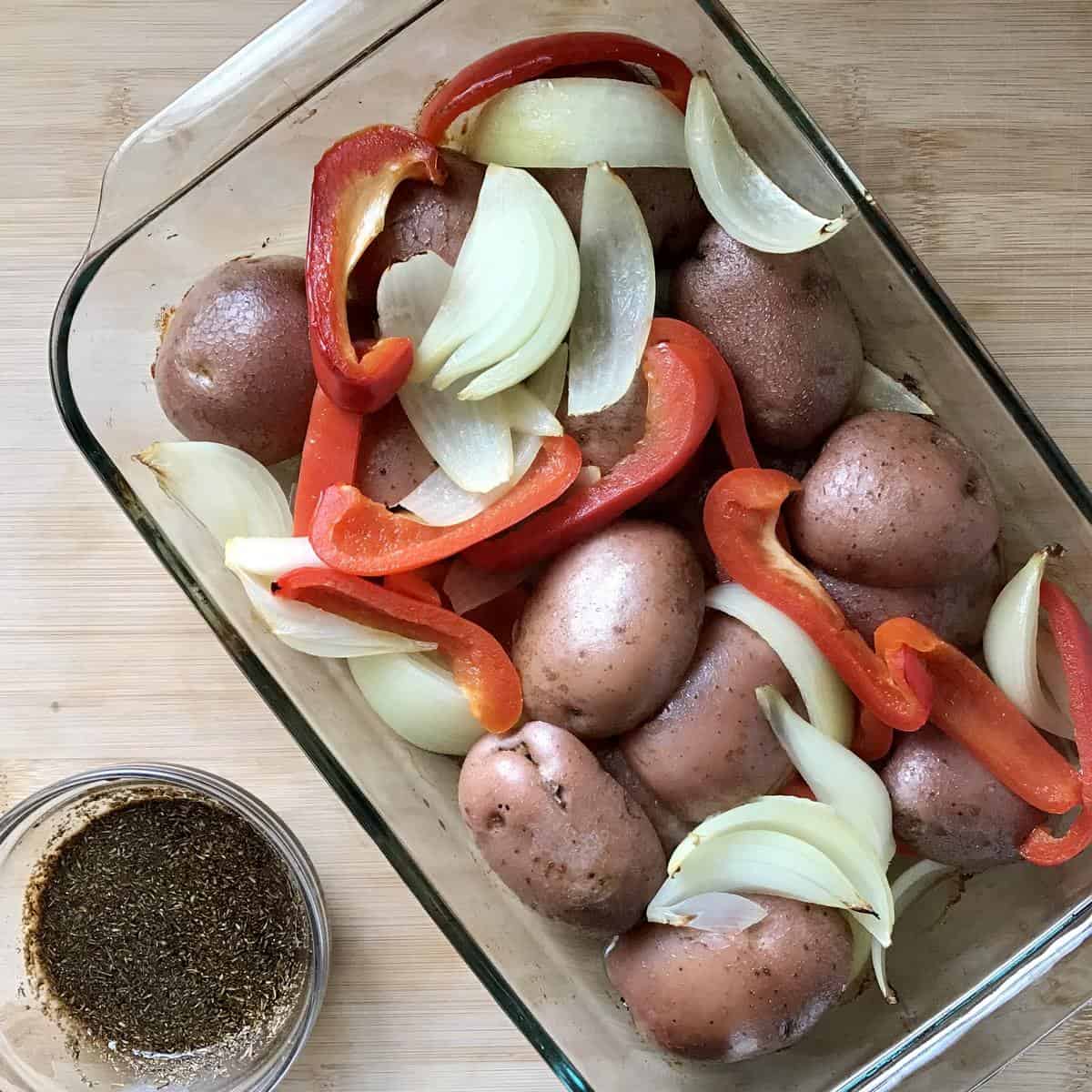 Baked vegetables next to a bowl of balsamic vinaigrette.